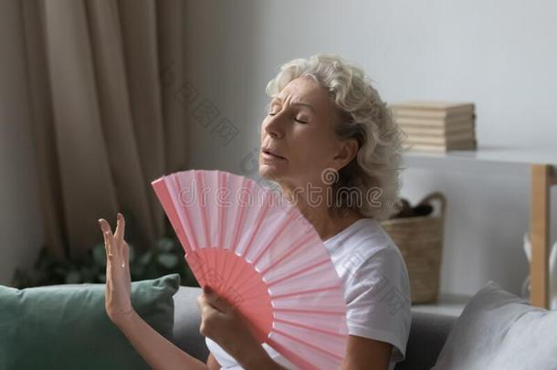 强调中部老年的退休的女人使用纸扇子.