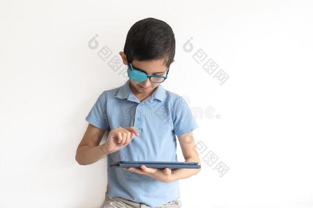 肖像关于男孩采用眼镜和补丁为眼镜.男孩和tablet药片