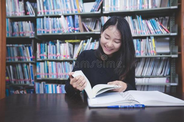 亚洲人女孩<strong>学生</strong>阅读书和使用笔记簿采用指已提到的人librarian图书<strong>管理</strong>员