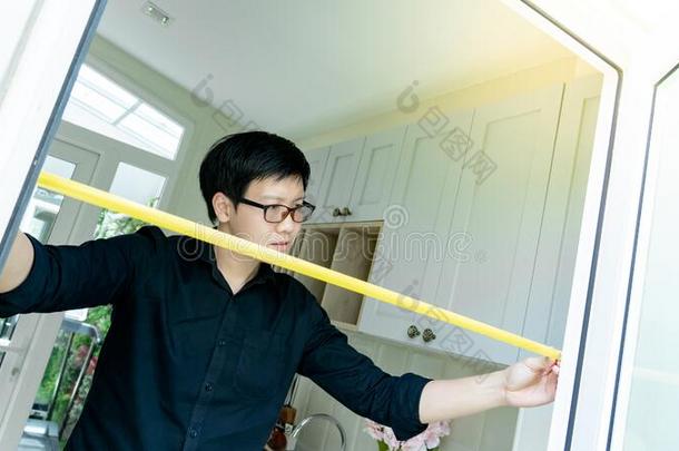 亚洲人男人使用带子测量向门框架