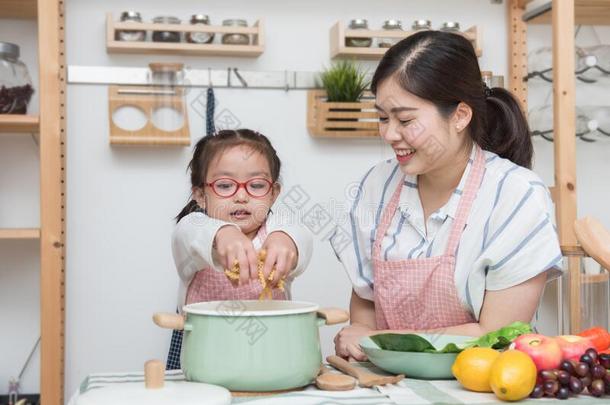年幼的亚洲人母亲教学怎样向烹饪术为女儿或西斯特