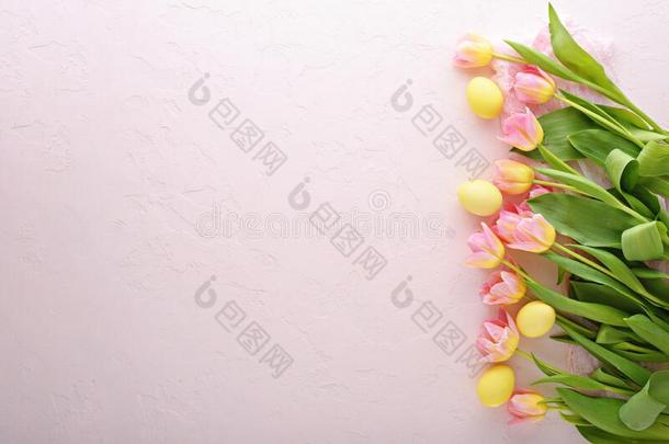粉红色的郁金香和黄色的复活节卵向粉红色的背景