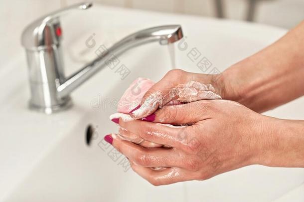 年幼的女人洗涤她手在下面水轻敲水龙头和肥皂.