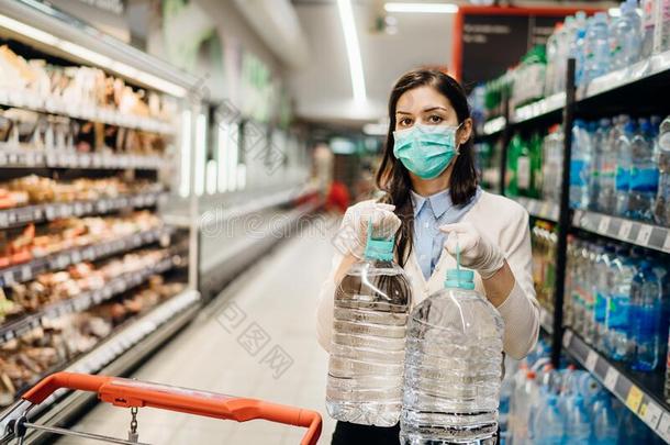 女人和面具安全地购物为食品杂货店在中间指已提到的人冠状病毒