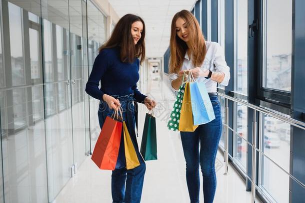 两个女孩-朋友向购物走向购物中心和袋