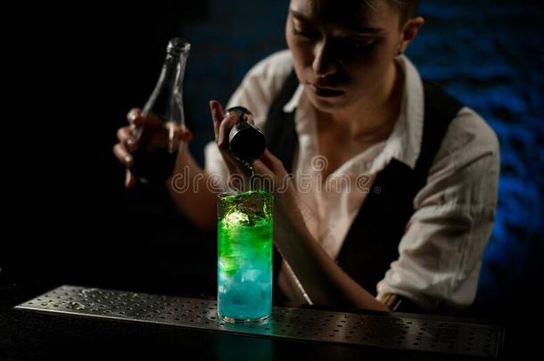专业的酒吧间销售酒精饮料的人加绿色的喝进入中玻璃向条伯爵