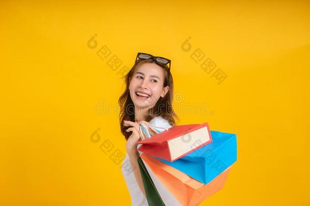 幸福的年幼的亚洲人女人和购物纸袋时尚购买