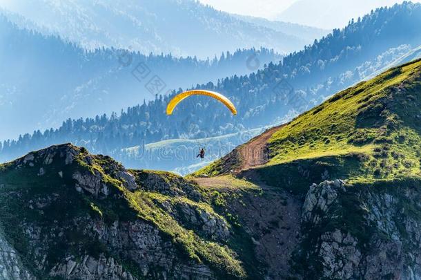 黄色的翼伞飞行器飞越过山斜坡向和煦的：照到阳光的夏一天