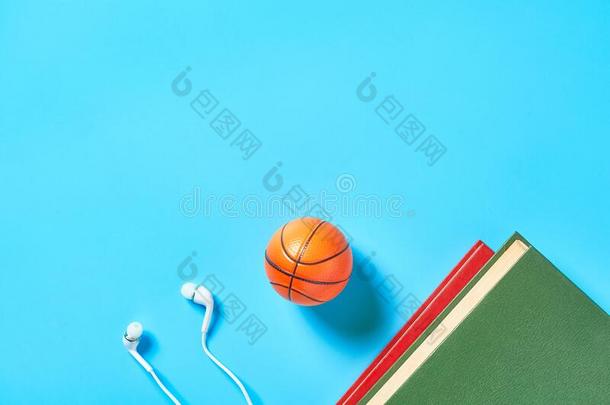 白色的戴在头上的收话器和老的书,玩具篮球球向蓝色后面