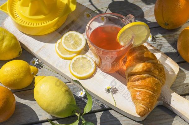 一杯子关于柑橘属果树成果茶水,羊角面包早餐,柠檬和猩猩