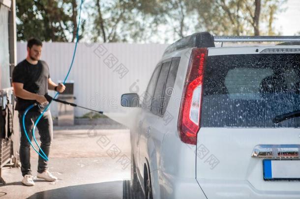 强的男人洗涤汽车在自己汽车wash在户外
