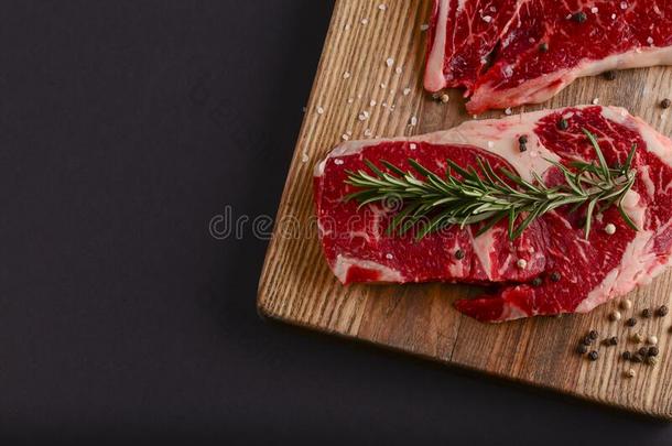 新鲜的生的牛肉牛排向木制的锋利的板越过黑的后台