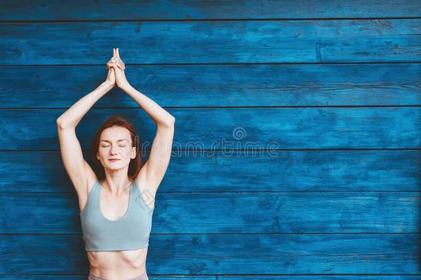 女人开业的瑜伽向背景关于蓝色木制的墙