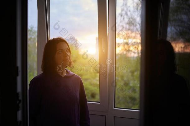 女人在近处窗在日落采用isol在ion在家为病毒外布