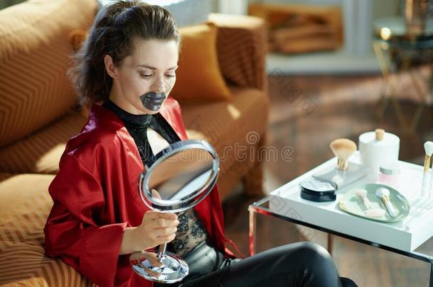 女人和镜子使用嘴唇面具采用现代的房屋采用和煦的：照到阳光的一天