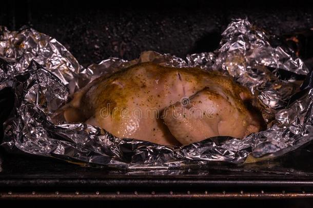 烹饪术烤全部的鸡采用箔采用热的烤箱特写镜头.多汁的