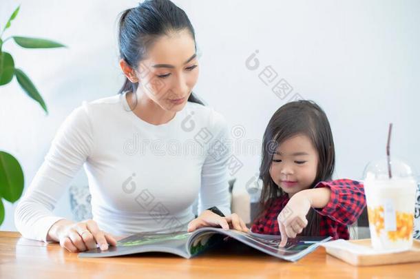 一亚洲人母亲是（be的三单形式教学她女儿向阅读一书在的时候英语字母表的第20个字母