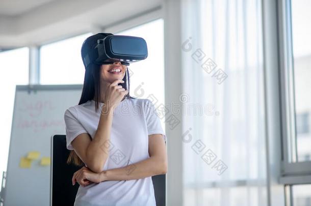 黑暗的-有毛发的女孩起立使人疲乏的VirtualReality<strong>虚拟现实</strong>戴在头上的耳机或听筒和<strong>微笑</strong>的