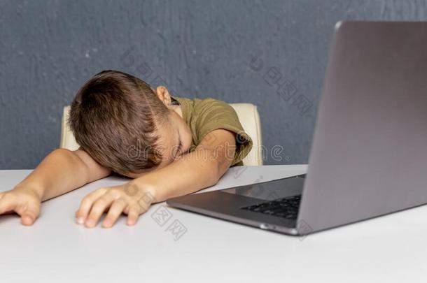疲倦的悲哀的男孩学习在家在线的向指已提到的人便携式电脑.距离lease租约