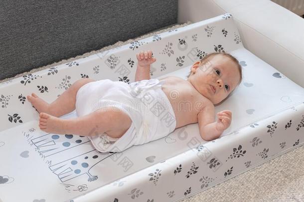 幸福的婴儿女孩说谎向尿布替换给装衬垫,使人疲乏的一尿布.