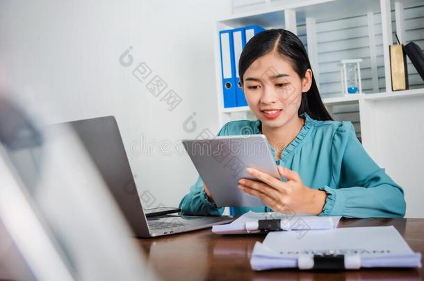 年幼的亚洲人女人工作的向便携式电脑和碑财政的工作的