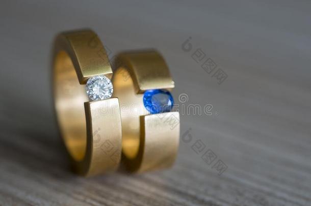 特写镜头关于对金色的婚礼戒指和钻石和蓝宝石