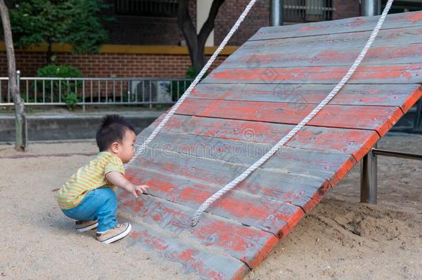 亚洲人蹒跚行走的人男孩演奏采用户外的操场