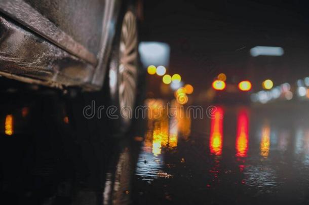 黑的汽车向指已提到的人湿的下雨的路在夜