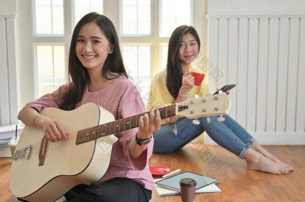 亚洲人十几岁的女儿是唱歌和演奏吉他.他/她/它们停留在