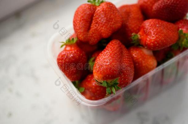 新鲜的有机的草莓采用一pl一stic盒向一白色的b一ckgroun
