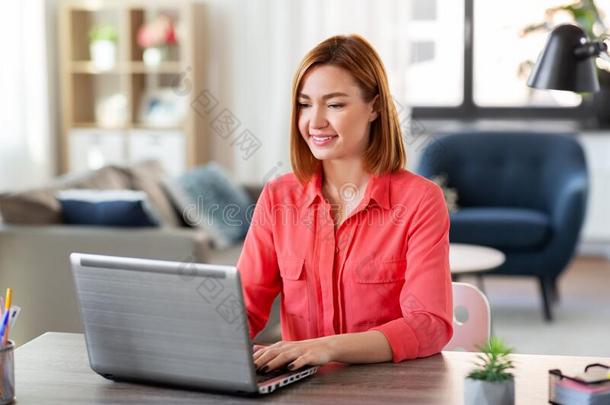 幸福的女人和便携式电脑工作的在家办公室