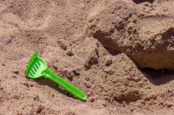 特写镜头关于绿色的玩具耙子向海滩沙背景和复制品休闲健身中心
