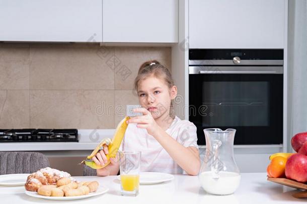 漂亮的悲哀的<strong>青春</strong>期前的女孩吃香蕉为早餐采用指已提到的人kitchen厨房