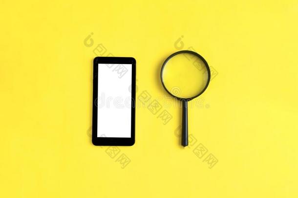 智能手机和放大的玻璃向黄色的背景.工作或influence影响