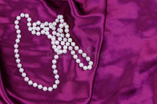 珍珠项链向紫色的缎织物背景
