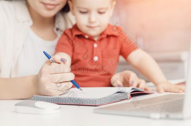 母亲教学她小孩儿子怎样向写笔.观念在线的草地