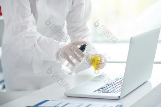 人采用保护的工作服spary采用g消毒杀菌剂向指已提到的人便携式电脑