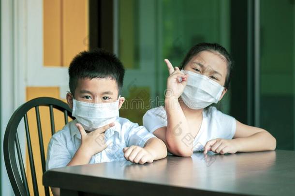 亚洲人孩子们使人疲乏的保护面具检疫期在家白色的