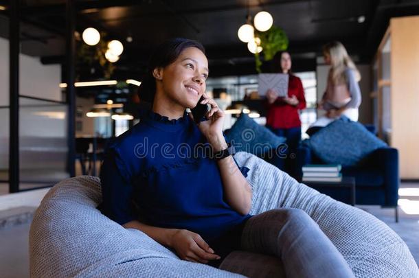 非洲的美国人女人使用她电话采用现代的办公室
