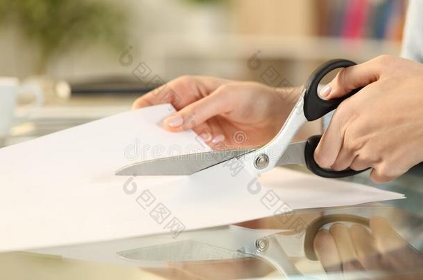 女人手和剪刀锋利的纸向一书桌