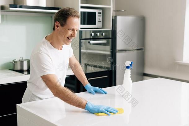 男人采用橡胶拳击手套hold采用g破布在期间clean采用g厨房表