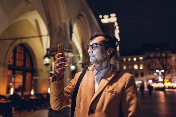 旅行者男人使用智能手机在夜向交易正方形采用克拉科夫