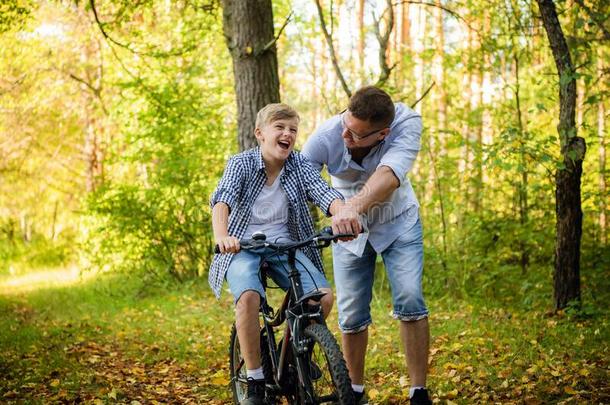 年幼的父亲教学他的微笑的儿子怎样向乘一自行车