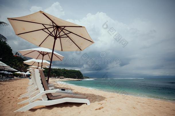 椅子和白色的雨伞向指已提到的人海滩.横幅.夏.旅行,休假