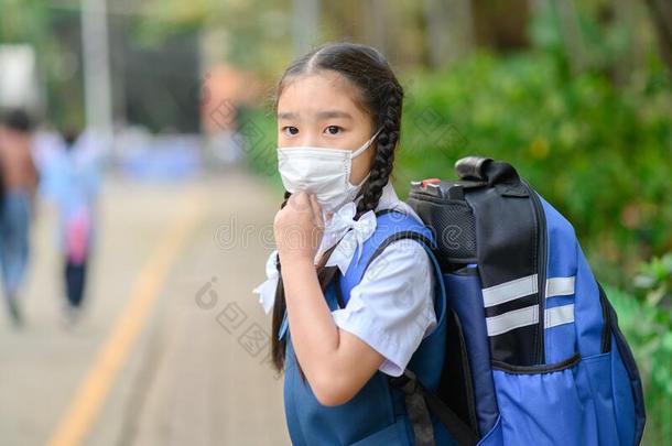 背向学校.亚洲人孩子们女孩穿着面具向保护为