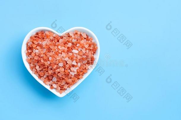 粉红色的喜玛拉雅的盐采用心形状碗向蓝色背景