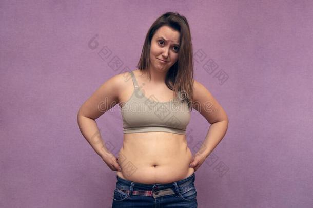 超重的女人手收聚过度的肚子肥的向粉红色的后面