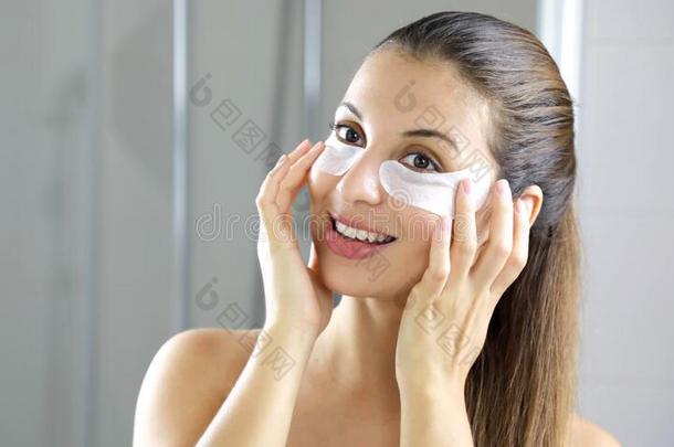微笑的美丽的女人应用反对者-疲劳在下面-眼睛面具厕所