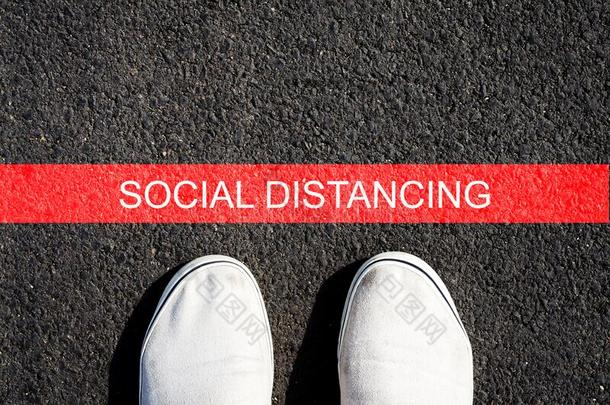 社会的距离.旅游鞋向沥青和一红色的线条.