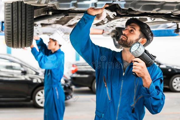技工和他的助手仔细检查指已提到的人汽车底部和使闪光英语字母表的第12个字母